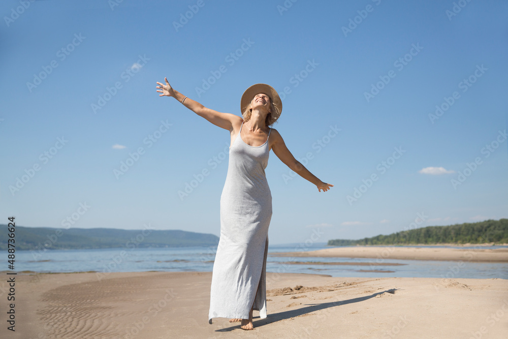 summer time lifestyle. portrait of an elderly woman in a straw hat dances on the beach in the summer summer time lifestyle. portrait of an elderly woman in a straw hat dances on the beach in the summer