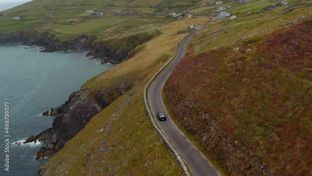 High angle view of single car driving on narrow country road along sea coast. Slea Head peninsula. Ireland High angle view of single car driving on narrow country road along sea coast. Slea Head peninsula. Ireland