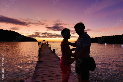 Silhouette middle aged couple relaxing on wooden pier in holiday at koh kood ,Thailand.
