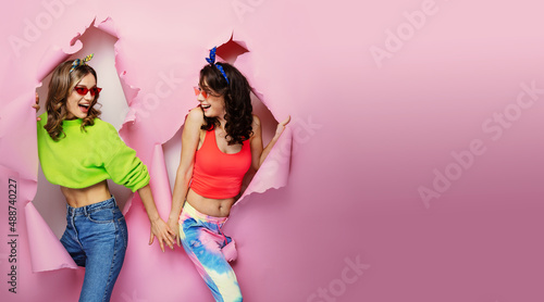 Girls coming out hole in paper background. Fitness, sport, fashion concept.