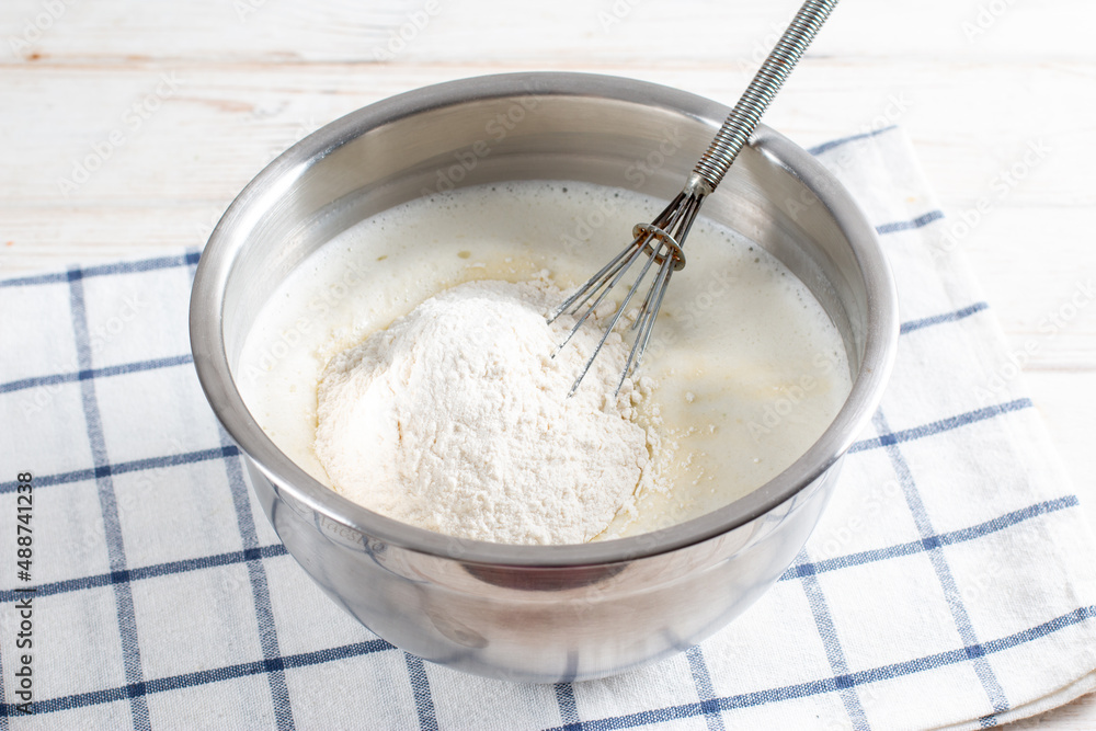 Cooking dough for traditional thin pancakes. Eggs, flour, salt, sugar, milk and butter in a bowl on a white wooden background. Recipe step by step. Food for Maslenitsa Cooking dough for traditional thin pancakes. Eggs, flour, salt, sugar, milk and butter in a bowl on a white wooden background. Recipe step by step. Food for Maslenitsa