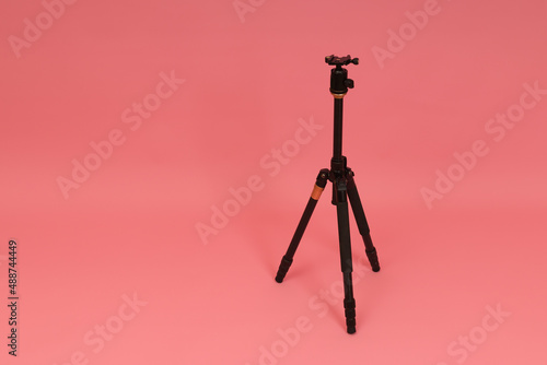 Fototapeta black tripod for camera on pink background with copy space