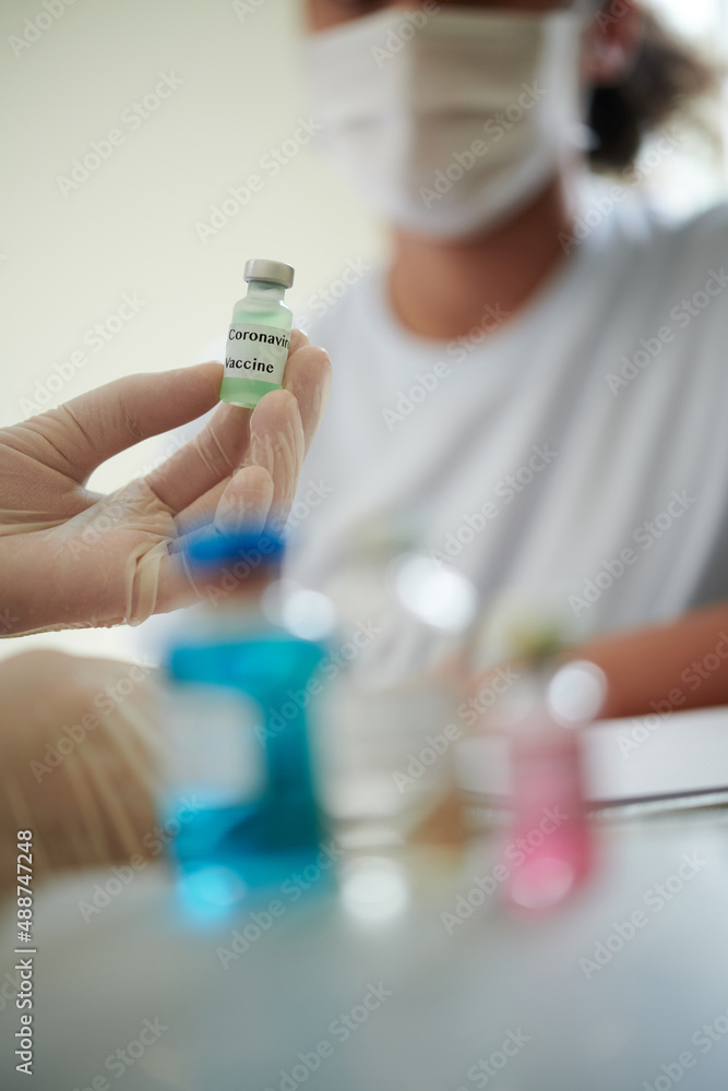 Fototapeta premium Close-up of doctor holding bottle with medicine and suggesting the vaccination to patient