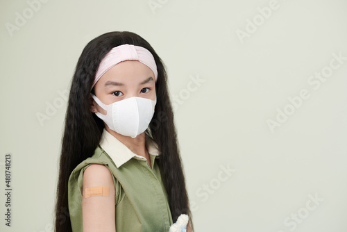 Portrait of ASian little girl in protective mask looking at camera against the white background © DragonImages