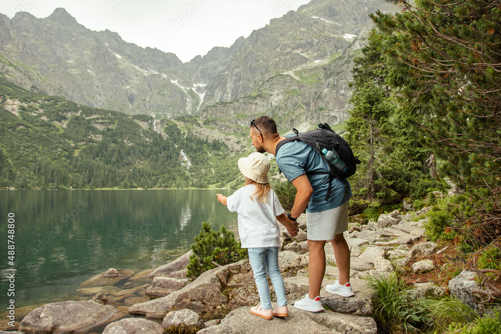 Man and child tourists in mountains at Morskie Oko lake near Zakopane, Tatra Mountains, Poland. Family travel concept. - obrazy, fototapety, plakaty 