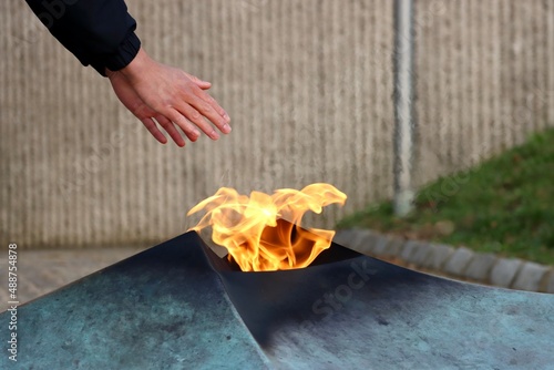 Man warming hands over Eternal fire of National Monument of the Solidarity in Luxembourg which commemorates dead of World War 2. Cold winter day