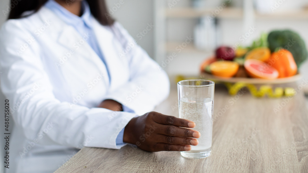 Detox and cleansing concept. Female nutritionist holding glass of water, recommending drinking daily amount of water Detox and cleansing concept. Female nutritionist holding glass of water, recommending drinking daily amount of water
