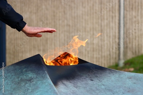 Man warming hands over Eternal fire of National Monument of the Solidarity in Luxembourg which commemorates dead of World War 2. Cold winter day