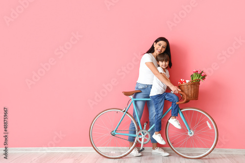 Little son and his mother with bicycle on color background © Pixel-Shot