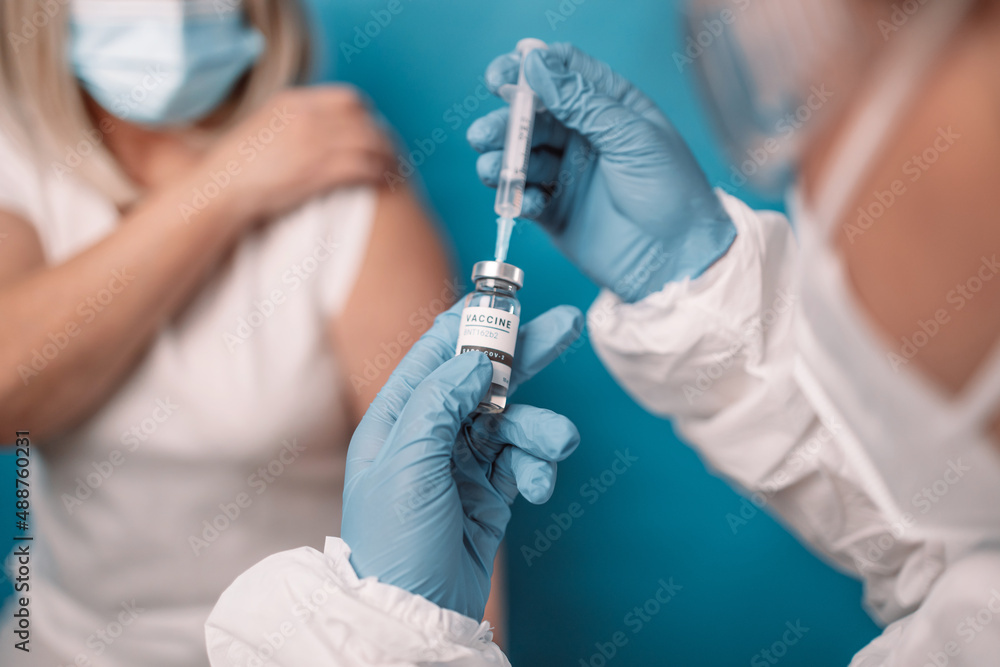 Close up of doctor or nurse hands taking covid vaccination booster shot or 3rd dose from syringe. Close up of doctor or nurse hands taking covid vaccination booster shot or 3rd dose from syringe.