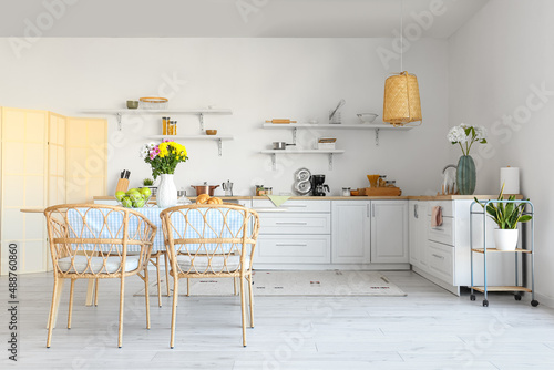 Interior of modern kitchen with dining table and beautiful Chrysanthemum flowers © Pixel-Shot