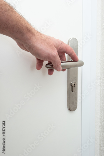 Caucasian male hand opening a door lever from inside apartment. Close up interior shot, no face.