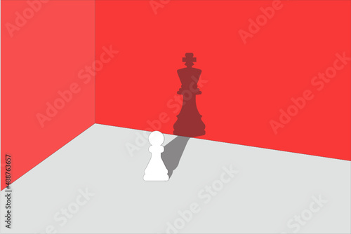 Chess pawn standing in a spotlight that make a shadow of king. trust yourself, self confident concept with wall