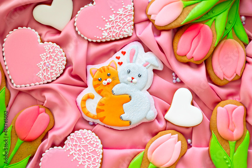 background banner greeting card for international women day or valentines day with cat and rabbit hugs, tulips and pigeon shape gingerbread cookies on pink silk fabric background