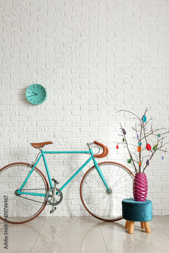 Tree branches with Easter decor and bicycle near white brick wall