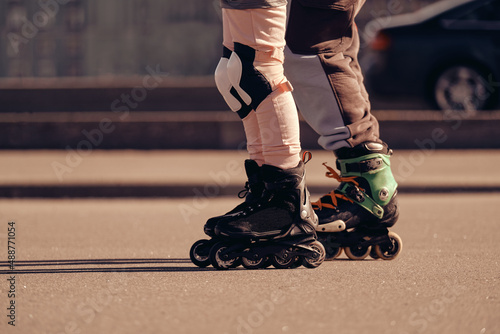 Two roller skaters ride on roller skates next to the road.