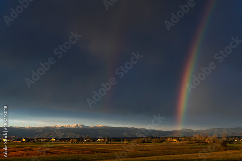 Huge rainbow over the Tuscan countryside against a dark cloudy sky, Bientina, Pisa, Italy