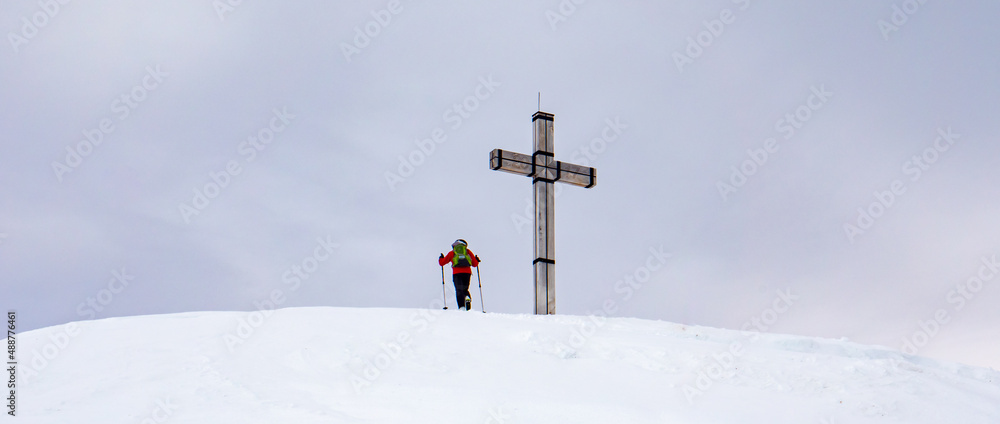 Panorama Bergsteiger auf einem Gipfelkreuz in den Alpen Panorama Bergsteiger auf einem Gipfelkreuz in den Alpen