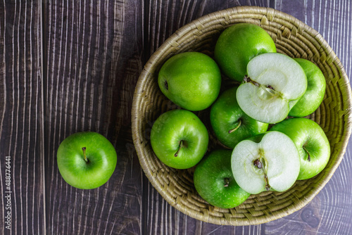 Top view of green apple in a basket on wooden table, green apple cut in half
