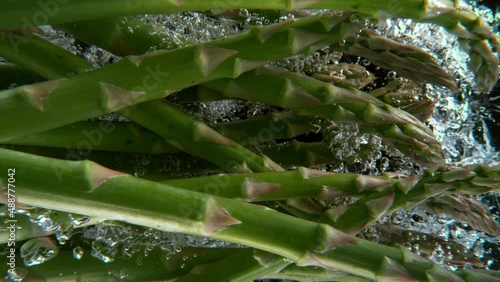 Super slow motion shot of falling asparagus into water, black background. Filmed on high speed cinematic camera at 1000 fps.