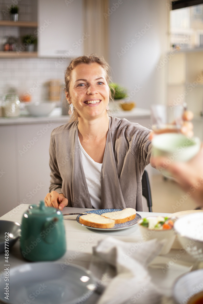 Beautiful woman enjoying in breakfast. Happy young woman eating sandwich at home.