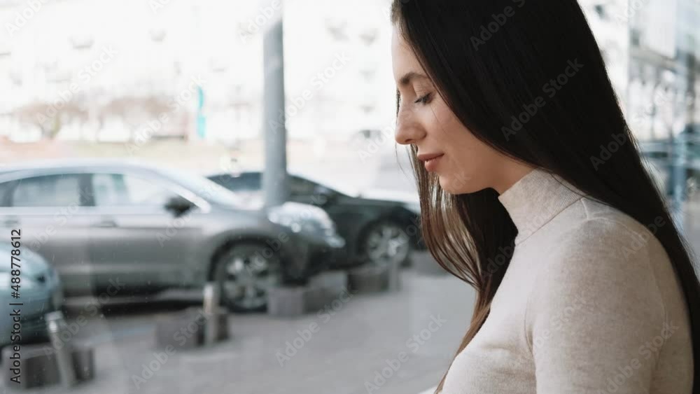Young woman using a smartphone sitting in a cafe near a big window and watching Young woman using a smartphone sitting in a cafe near a big window and watching