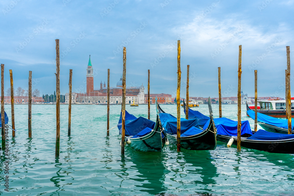 December 2, 2021 - Venice, Italy: Gondolas moored at San Marco Gondola Service Station on Grand Canal with Chiesa di San Giorgio Maggiore on the background.