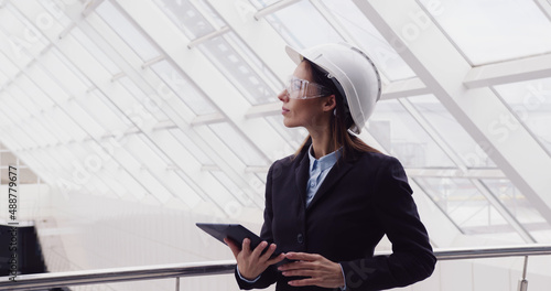 Successful intelligent woman architect standing at new office center using tablet to look at building plan drawing. Female engineer working at construction site.