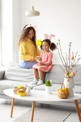 Little African-American girl with Easter rabbit and her mother at home