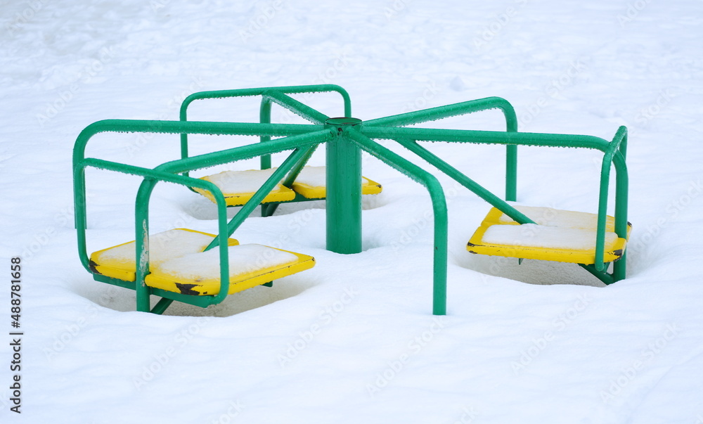 Children's carousel in snow and in drops of melt water Children's carousel in snow and in drops of melt water