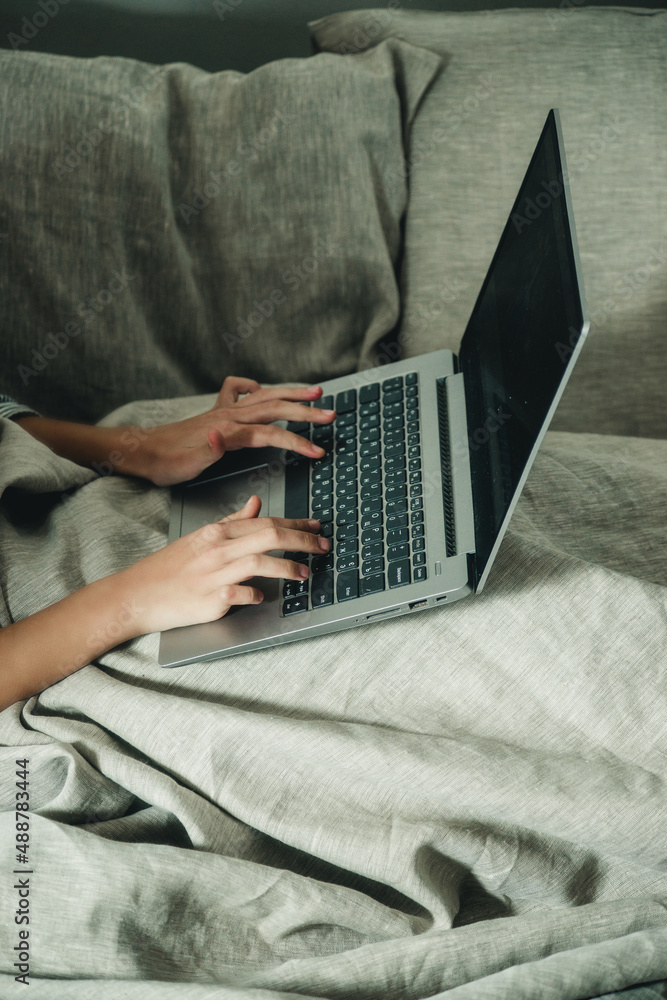 Fototapeta premium hands and laptop on the bed close-up