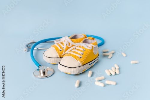 The concept of children's health and treatment. Children's shoes with stethoscope. Place for text © KseniaJoyg
