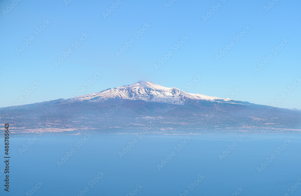 Aerial view of Mount Etna, an active volcano in Sicily, with snow capped mountain peak and Catania city, from the Mediterranean sea