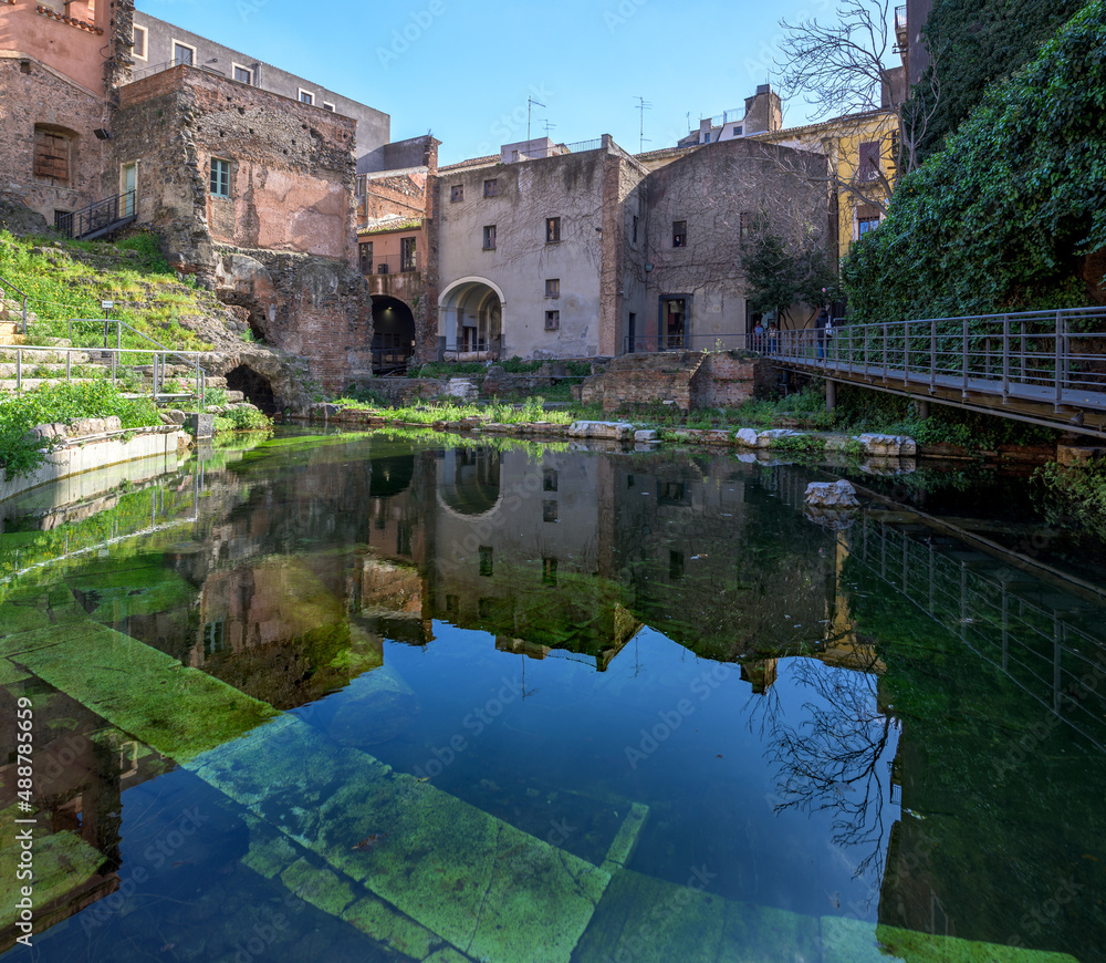Roman theater, Catania, Italy. Old Roman amphitheater and Baroque style buildings, with a stage pond covered in vegetation and stone grandstands in Catania city center, Sicily, Italy
