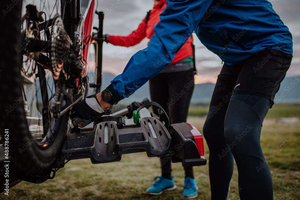 Active senior couple loading their bicycles on car carrier outdoors in nature in autumn day. Active senior couple loading their bicycles on car carrier outdoors in nature in autumn day.