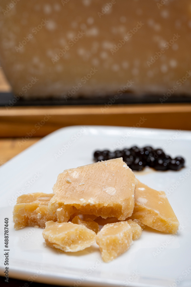 Tasting of 72 months very old Italian parmigiano-reggiano parmesan cheese from Parma with extremely grainy and crumbly structur with black pearls of balsamic vinegar DOP from Modena. Tasting of 72 months very old Italian parmigiano-reggiano parmesan cheese from Parma with extremely grainy and crumbly structur with black pearls of balsamic vinegar DOP from Modena.