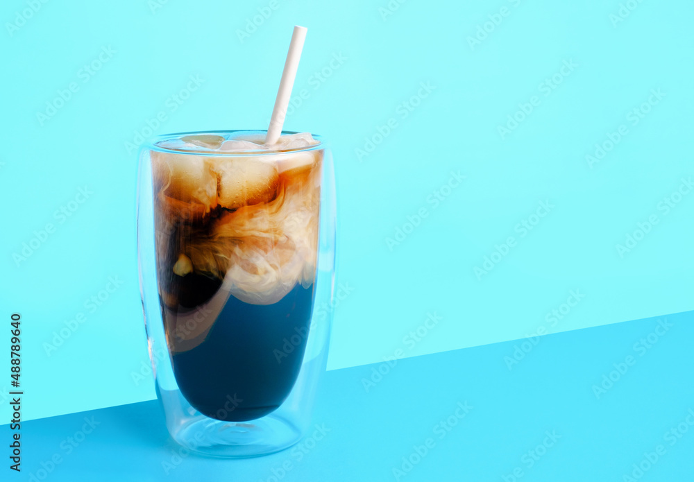 Coffee with milk and ice in glass cup on blue background, copy space. Coffee with milk and ice in glass cup on blue background, copy space.