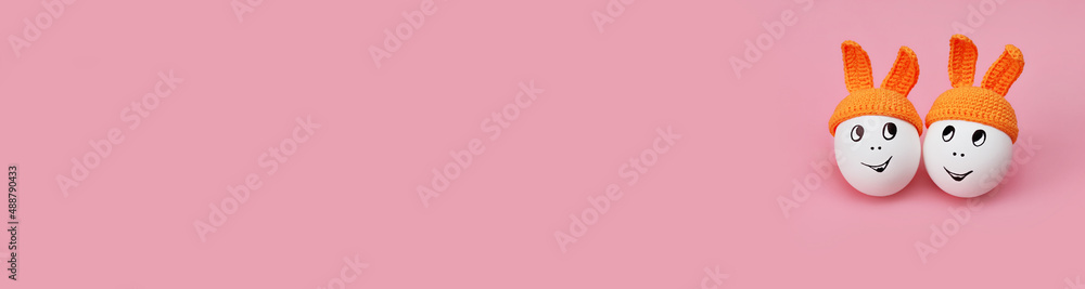banner two white eggs in beanie with rabbit ears and cheerful faces on pink background banner two white eggs in beanie with rabbit ears and cheerful faces on pink background