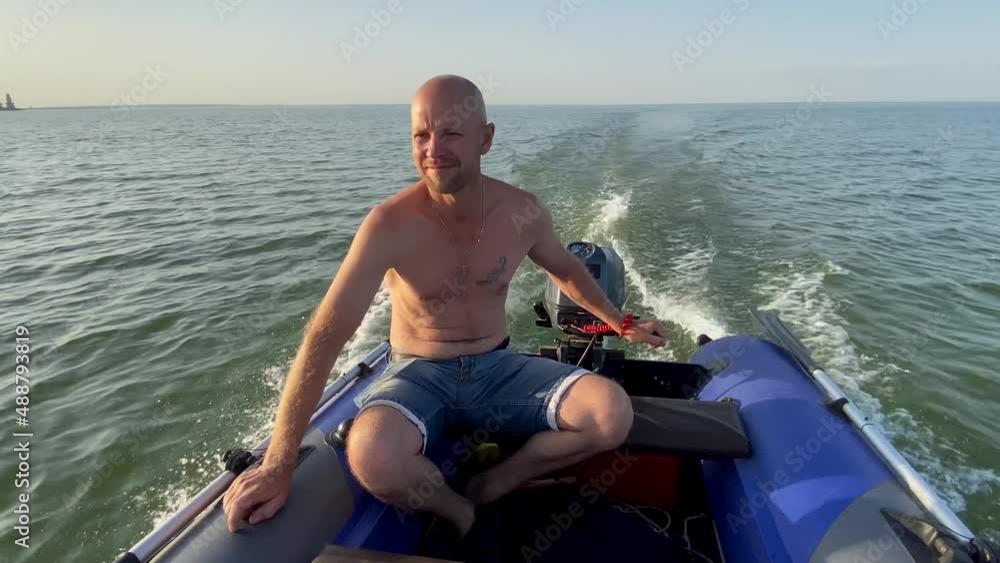 Happy Adult man sailor drives a motorized rubber inflatable boat. Planning. Waves on water. Boat trip on river at high speed. The concept of freedom and movement. Fishing trip. Happy Adult man sailor drives a motorized rubber inflatable boat. Planning. Waves on water. Boat trip on river at high speed. The concept of freedom and movement. Fishing trip.