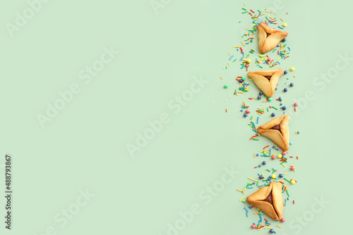 Purim celebration concept (jewish carnival holiday). Hamantaschen cookies over pastel green background. Yop view photo