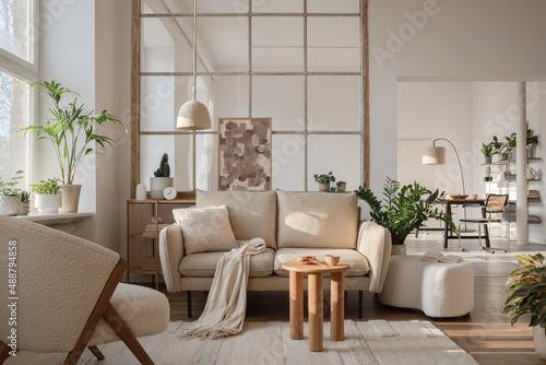 Modern living room interior composition with beige sofa, wooden coffee table and modern home accessories. Template. Copy space. Dining room in the background. © FollowTheFlow