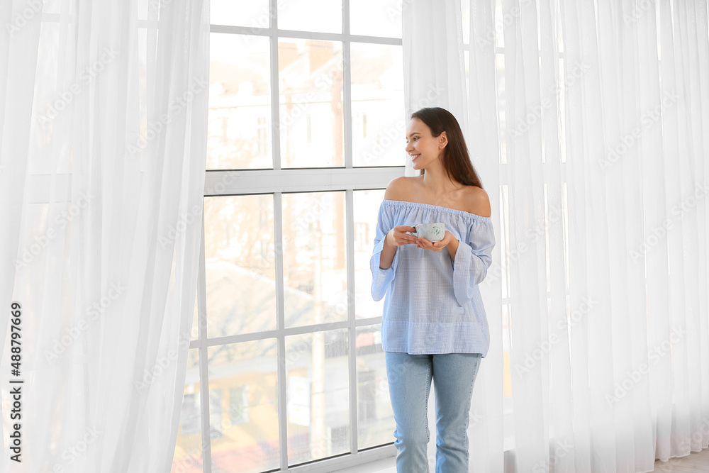 Morning of pretty young woman drinking tea near window Morning of pretty young woman drinking tea near window