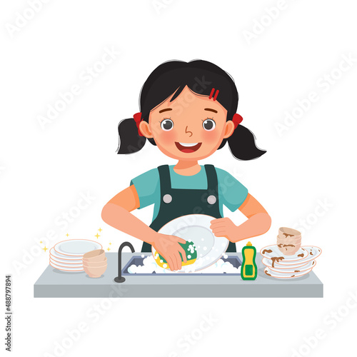 Little girl washing dishes at sink in the kitchen doing housework chores at home