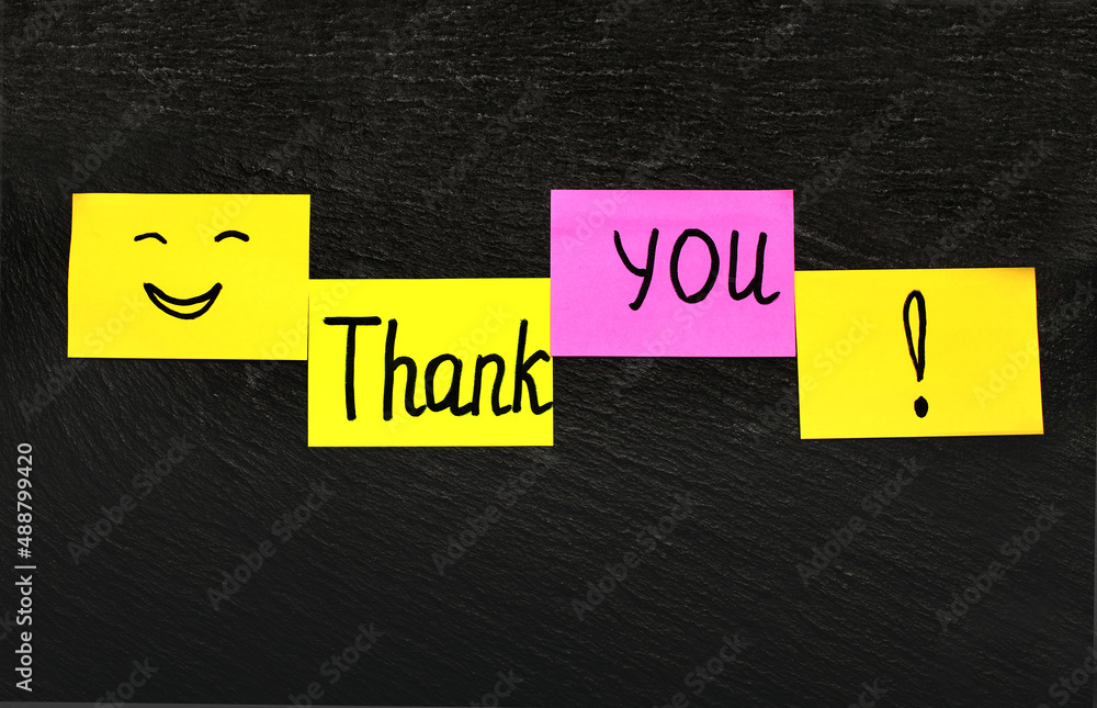 Thank you inscription on colored sticky paper chaotically attached to a ...