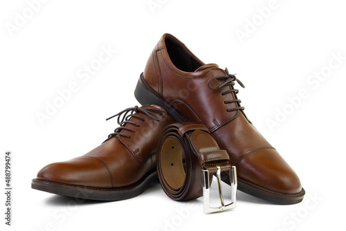 Pair of unbranded brown genuine leather shoes and rolled belt isolated on white background, closeup. Fashion and shopping concept