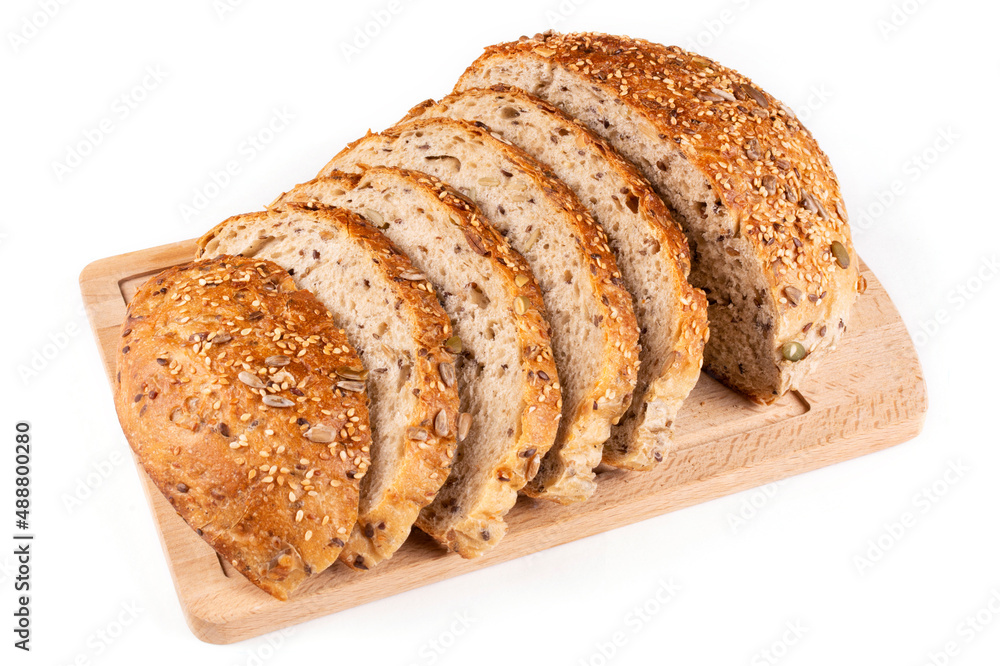 Round bread made of whole wheat flour with pumpkin seeds, sesame seeds, flax and sunflower is sliced on a wooden board on a white insulated background. Pattern. Bread without yeast, with sourdough.
