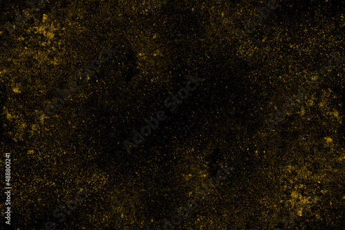 Scattered spread yellow dust particles on black background