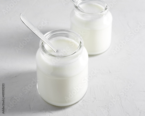 Yogurt, kefir or fermented milk product in glass jars on a white table. Healthy food concept