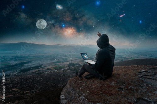 Fotografie digital nomad sitting on the top of the mountain with a laptop at night