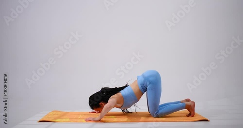Young woman practicing surya namaskara yoga pose over white background photo